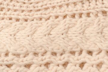 A fragment of beige knitted fabric, knitted from white sheep wool.