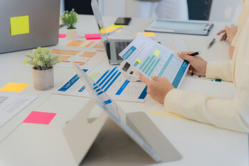 Business colleagues reviewing financial data during a meeting to discuss financial strategies. Reviewing data on laptops and documents for market analysis in the office. Close-up.