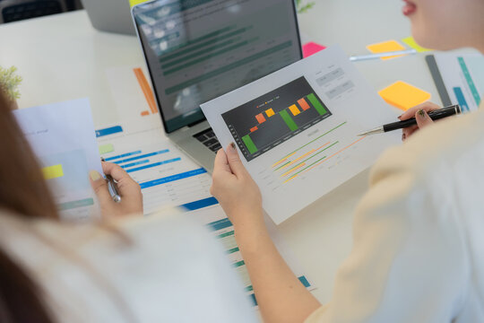 Business colleagues reviewing financial data during a meeting to discuss financial strategies. Reviewing data on laptops and documents for market analysis in the office. Close-up.