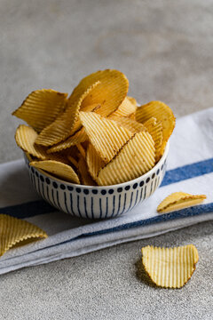Close-up of a Bowl with homemade potato crisps on a folded tea towel