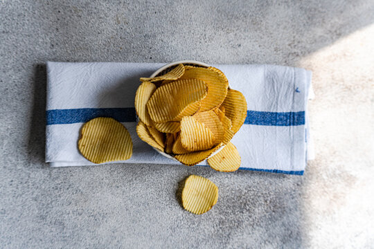 Close-up overhead view of a Bowl with homemade potato crisps on a folded tea towel