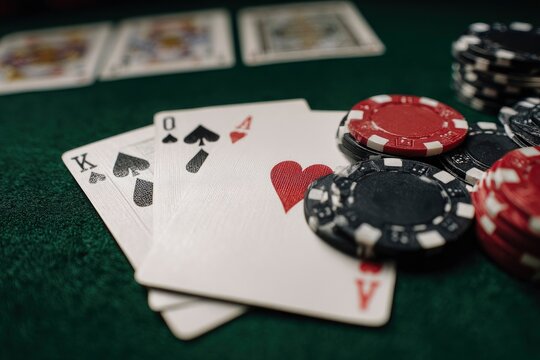 High angle captures a close-up of playing cards and poker chips on a green felt table, invoking