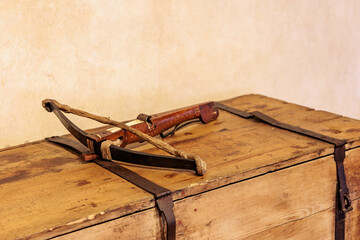 Rustic wooden crossbow on vintage wooden chest with leather straps