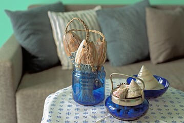 Marine style in the apartment interior - a sofa with pillows and a table with shells and fish figures.