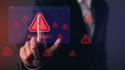 Hand pointing at digital warning alert icon on virtual screen, representing cybersecurity threat, data breach, system error, or online danger.