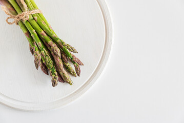 Fresh asparagus tied bundle on white table. Top view