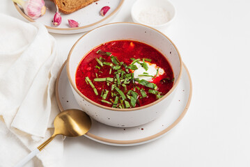 Traditional Ukrainian borscht with sour cream, garlic and rye bread on white table. Front view