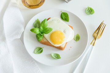 Fried egg on toast with fresh basil leaves.