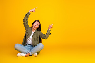 Young woman in casual style making gestures against yellow background presenting attitude and...