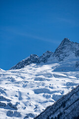Karachay-Cherkessia. Dombay 2025. Majestic snow-covered mountain peak stands tall against clear blue sky, showcasing rugged beauty of winter landscape. Nature concept for design.