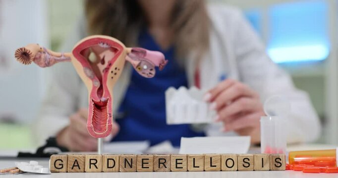 Word Gardnerellosis of wood cubes by uterus model and suppository in clinic. Woman gynecologist examines female reproductive system health in hospital