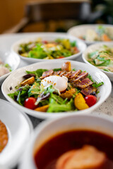 Fresh salad with mixed greens, cherry tomatoes, sliced seared tuna, roasted potatoes, and a poached egg, beautifully plated for a gourmet dining experience.