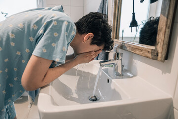 Teenager girl washing her face in the morning bathroom routine