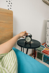Hands of a person unrecognizable stopping alarm clock in the morning