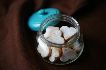 A glass jar filled with sugar-coated cookies shaped like hearts.