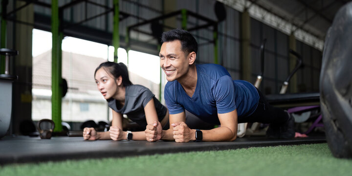 Wellness and Friendship. Friends engaged in a plank exercise at the gym.