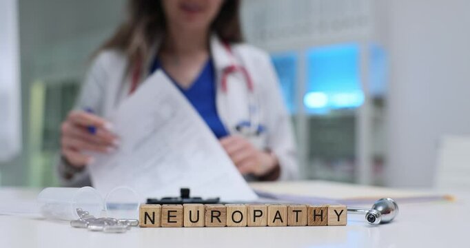 Female doctor writes prescription for Neuropathy disease treatment with pills and reflex hammer near wooden cubes. Woman works in clinical setting