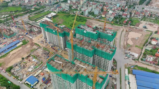 Wider aerial pull-back to show the tower site bordered by streets, storage yards and adjacent suburban villas under a grey sky