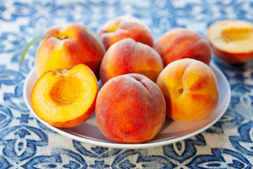 Fresh peaches on a white plate. Azulejo background. Close up.