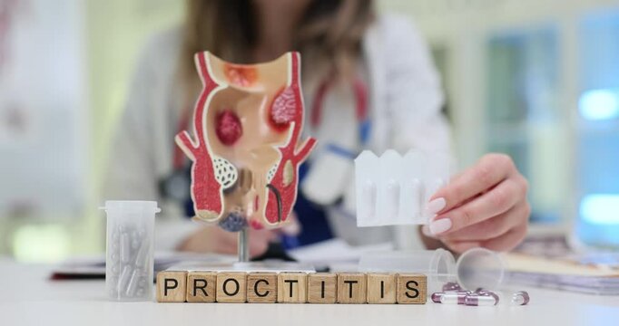 Proctologist holds suppositories for Proctitis treatment near anatomical model of rectum in medical office. Diagnosis and treatment of proctitis