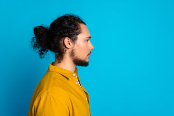 Profile view of a stylish young man with a beard and curly hair wearing a yellow shirt and staring...