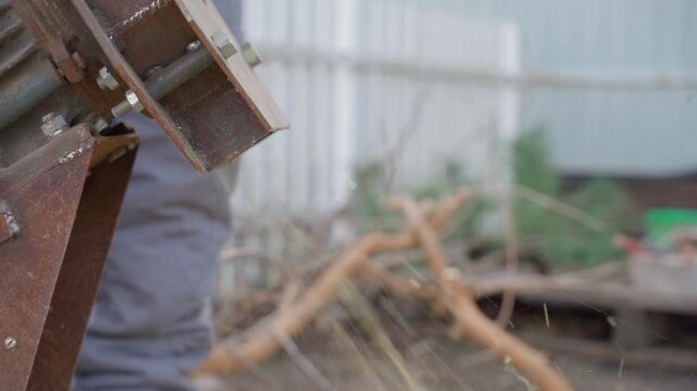 Homemade wood chipper for chopping branches spits out sawdust, close-up