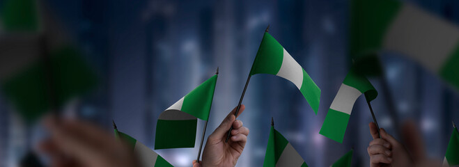 Nigeria flags in their hands on a blurred urban background