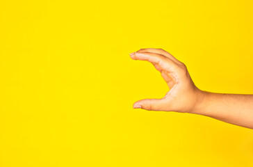 Studio Shot of Hand Reaching Out on Yellow Backdrop