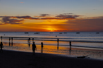 Obraz premium Beautiful colourful sunset on Kuta Beach on the island of Bali blue purple orange skies with turquoise blue waters and silhouette of people on the sandy beach the land of gods Bali Island Indonesia 