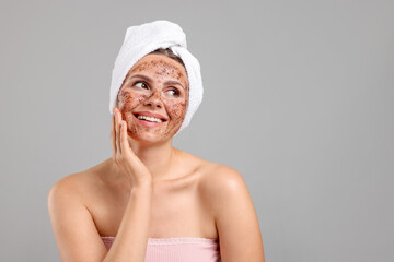 Smiling woman with body scrub on her face against grey background. Space for text