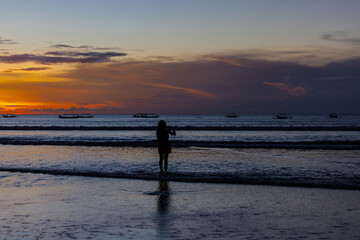 Fototapeta premium Beautiful colourful sunset on Kuta Beach on the island of Bali blue purple orange skies with turquoise blue waters and silhouette of people on the sandy beach the land of gods Bali Island Indonesia 