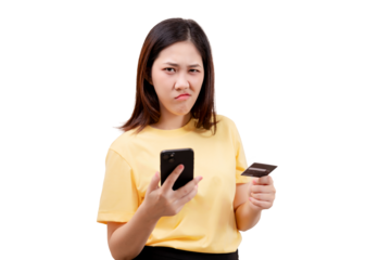 Asian young beautiful woman in a yellow shirt holds a smartphone and credit card, displaying a frustrated expression.