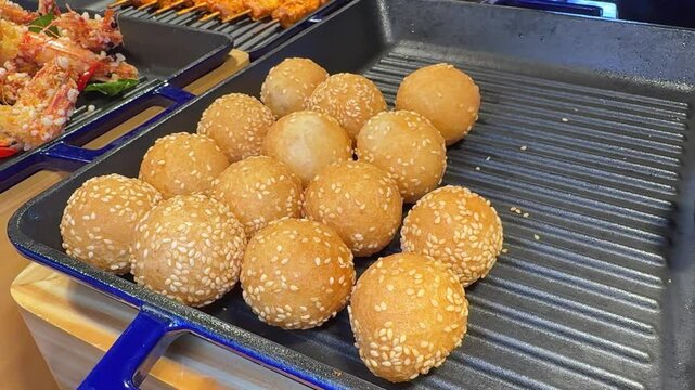 Traditional Chinese food Jian dui or sesame ball close-up. Fried Chinese pastry made from glutinous rice flour with sesame seeds. Local street food market outdoor. High quality 4k footage