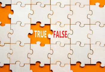 True or False symbol. Concept word True or False on wooden puzzle. Beautiful orange background....