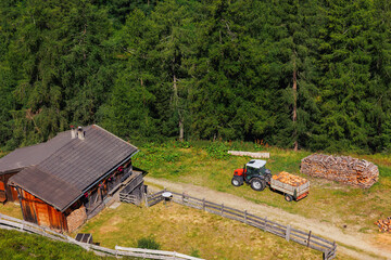 Scenic aerial view alpine village log wooden countryside cabin lumber stock lumber timber manufacture yard tractor machinery and storage. Rural landscape meadow wood piles forestry country vibe