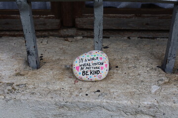 Window with metal bars and be kind kindness rock