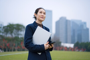 Confident Businesswoman with Laptop in City Park
