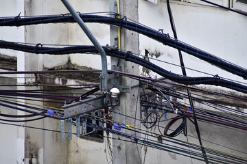 Close-up of messy electric cables on pole in Thailand. Entangled wires on an Electricity Pole. 