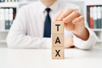Businessman with tax word on wooden blocks