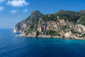 Obraz premium Stunning coastal cliffs of Corfu Island with crystal-clear turquoise waters and lush green hills — a must-visit Mediterranean paradise for nature and sea lovers