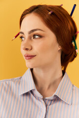 Young woman with colored pencils in her hair, showing her artistic flair against a bright backdrop