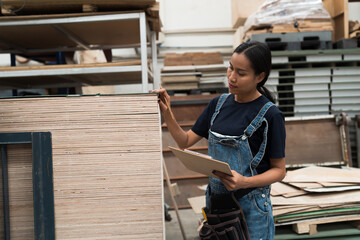Asian woman worker working in timber warehouse, checking inventory of timber in wood warehouse