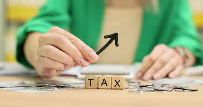 Accountant raises taxes with wooden cubes marked with Tax and upward arrow. Symbol of significant increase in tax rates and financial obligations