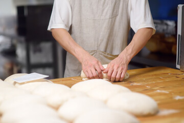 The bakery chef prepares the dough for baking bread. The baker kneads the dough and sets it to fit, baking eco-bread according to an old traditional recipe. Workflow in a local bakery