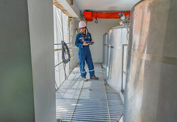 Male work inspection process stainless steel tanks and pipe with pressure meter in equipment tank facility for drink cellar at the with vertical stainless