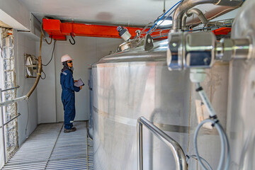Male work inspection process stainless steel tanks and pipe with pressure meter in equipment tank facility for drink cellar at the with vertical stainless