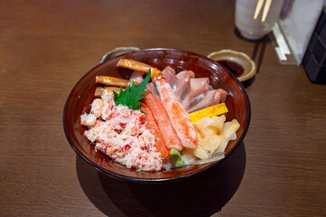 Premium fresh raw seafood mixed rice bowl (Kaisen-don, Japanese tasty food), Japanese Rice with sashimi of salmon, zuwai kani crab on wood background