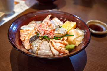 Premium fresh raw seafood mixed rice bowl (Kaisen-don, Japanese tasty food), Japanese Rice with sashimi of salmon grill, zuwai kani crab on wood background