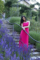 An attractive woman stands on the castle steps surrounded by colourful lavender. The girl is...