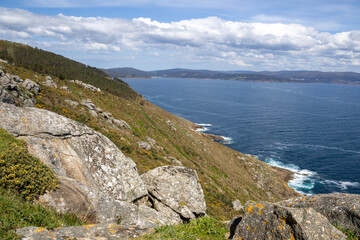 Finisterre Lighthouse on a rocky cliff in Galicia, Spain, overlooking the Atlantic Ocean at sunset....
